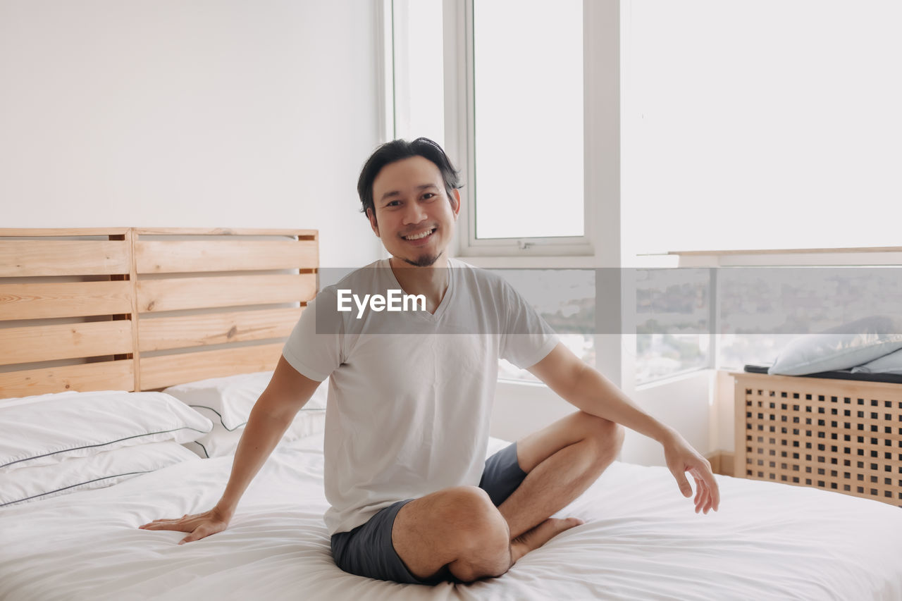 Portrait of smiling young woman sitting on bed