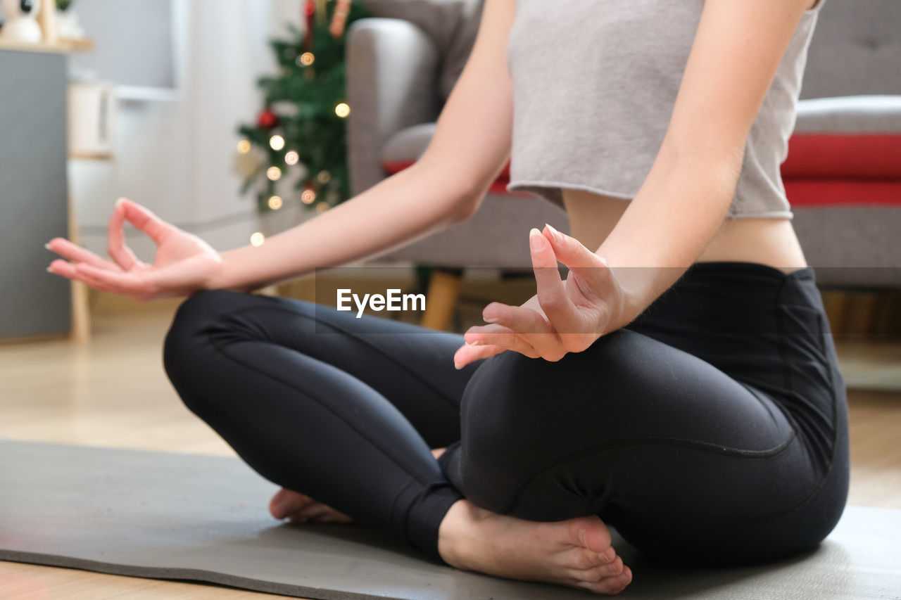 low section of woman doing yoga on exercise mat