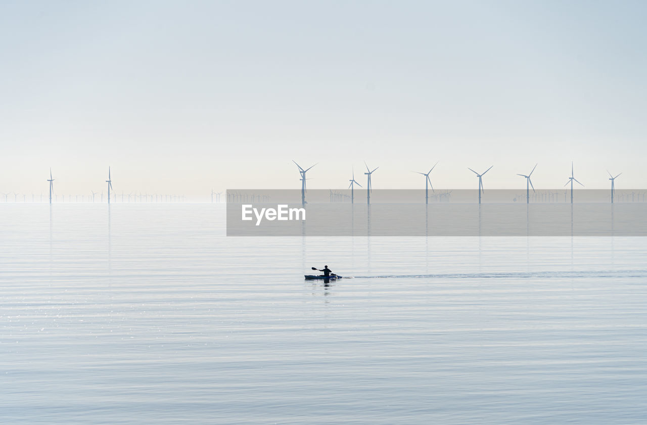 Offshore wind turbines generating renewable electricity and energy  atmospheric background image