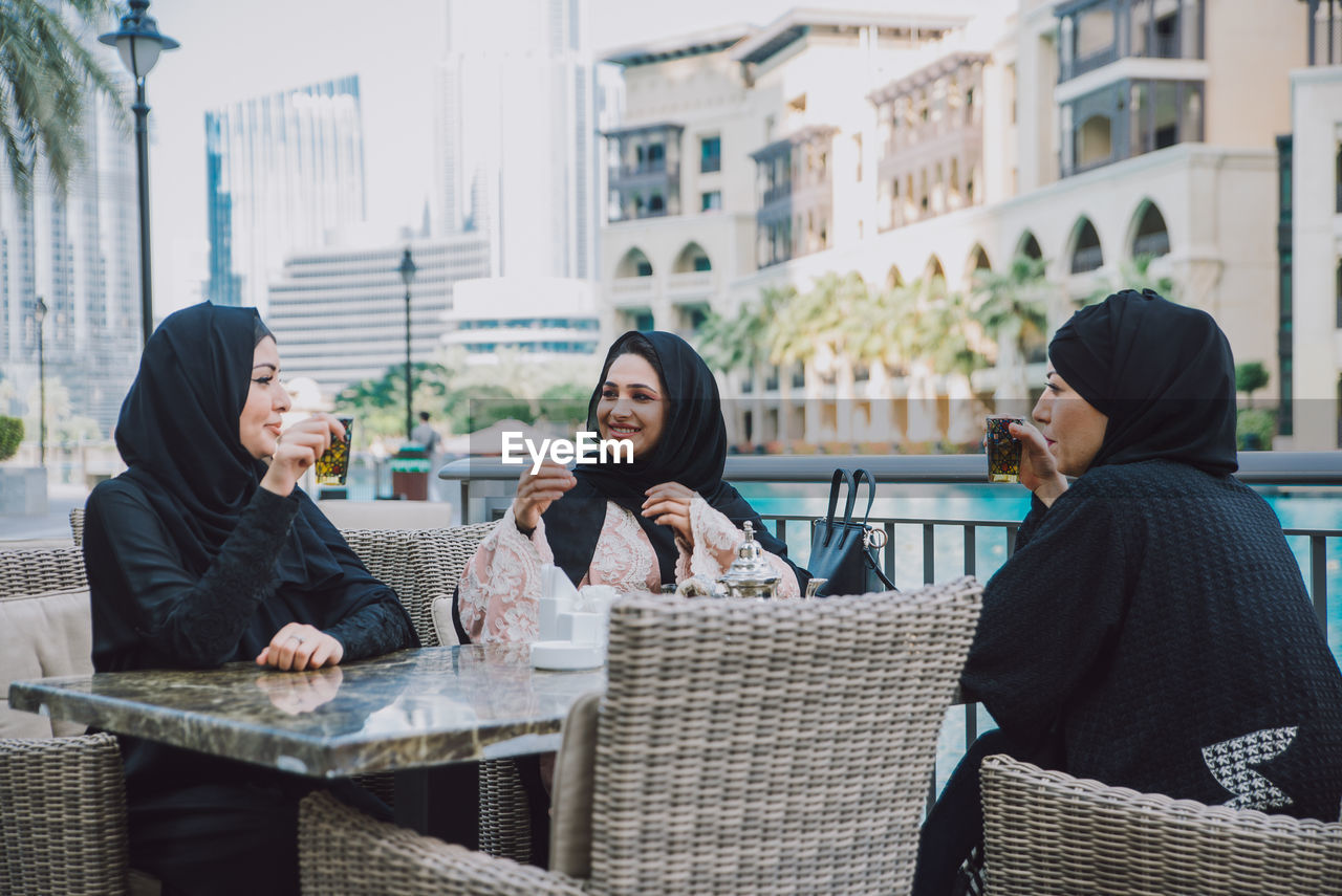 Smiling women in hijab sitting outdoors