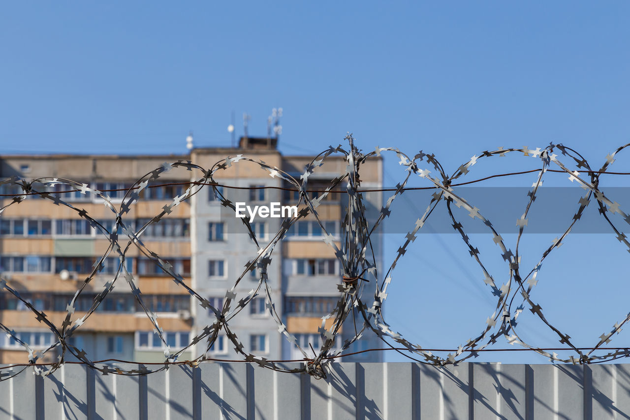 Residential multi-storey building behind a fence with barbed wire, concept of imprisonment