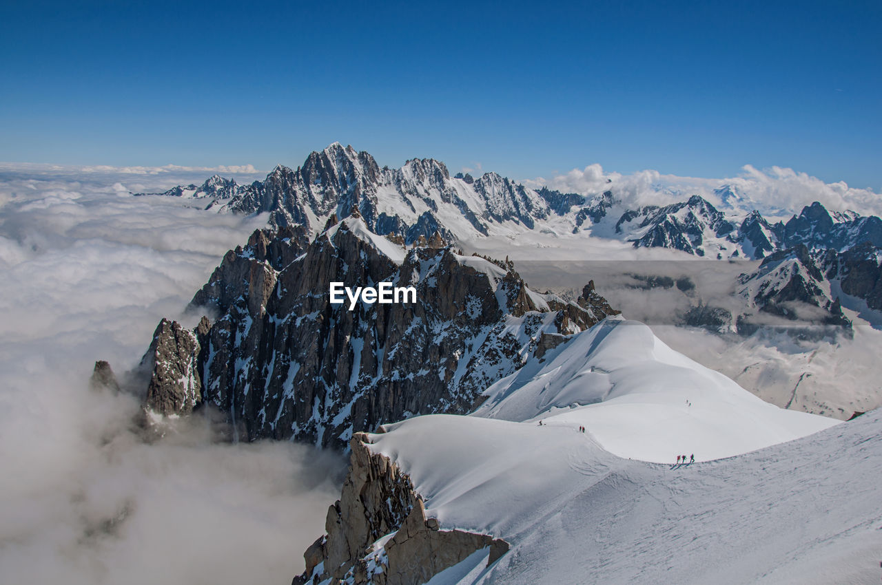 Snowy peaks and mountaineers in a sunny day at the aiguille du midi, near chamonix, france.