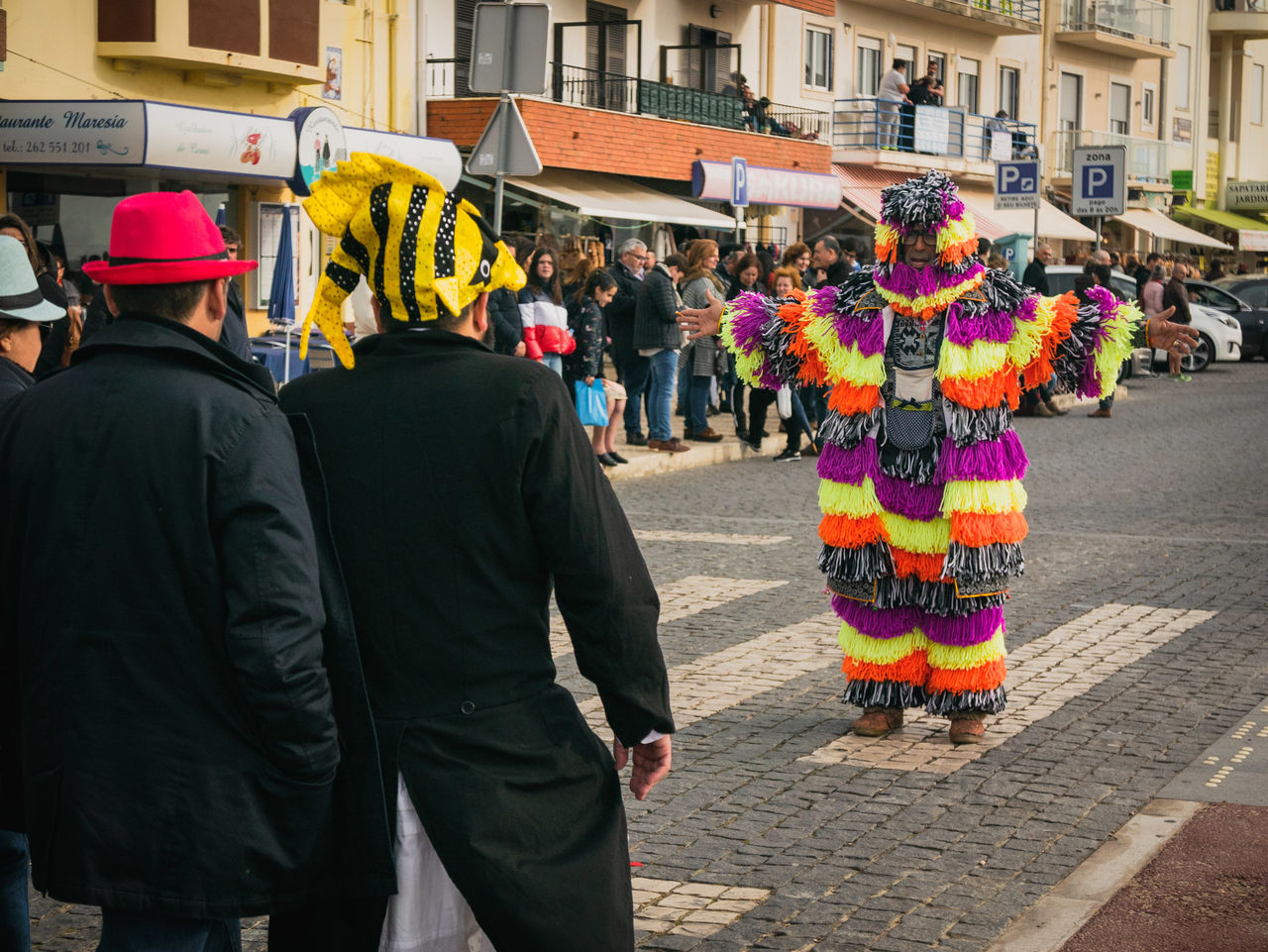 REAR VIEW OF PEOPLE WALKING ON STREET AGAINST CITY