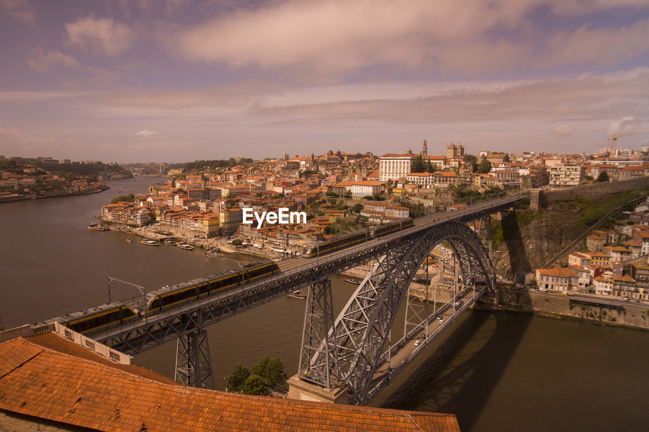 Trains on dom luis i bridge over douro river by city against sky