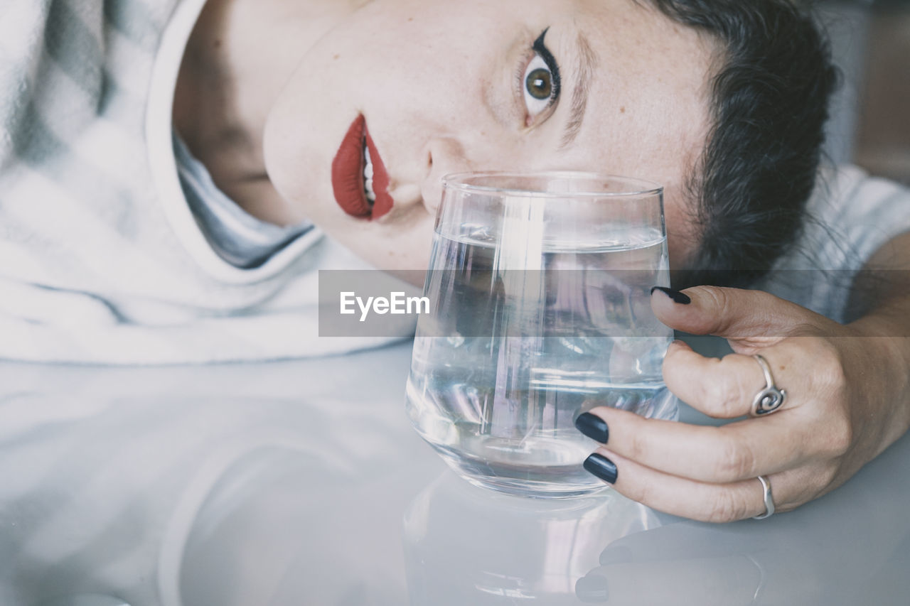 Close-up portrait of woman holding glass of water