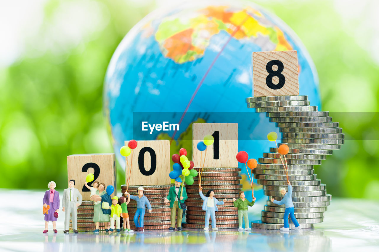 Close-up of toys with stacked coins and globe on table