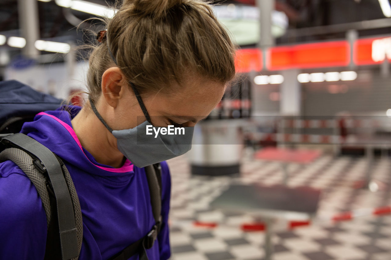 Female traveler with nose and mouth covering mask to comply with covid-19 regulations in airport.