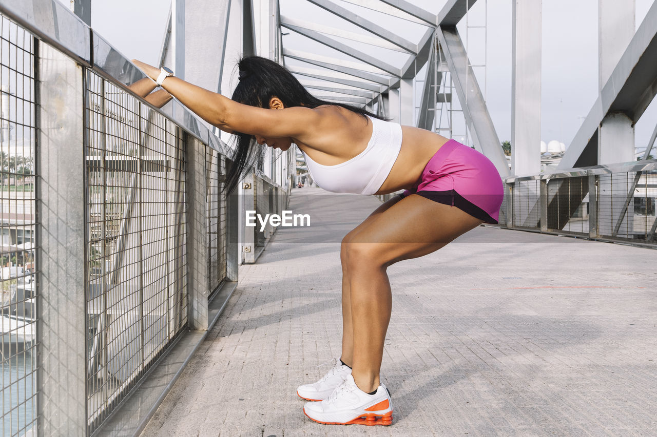 Attractive middle-aged sportswoman doing stretching, working out outdoors in the city