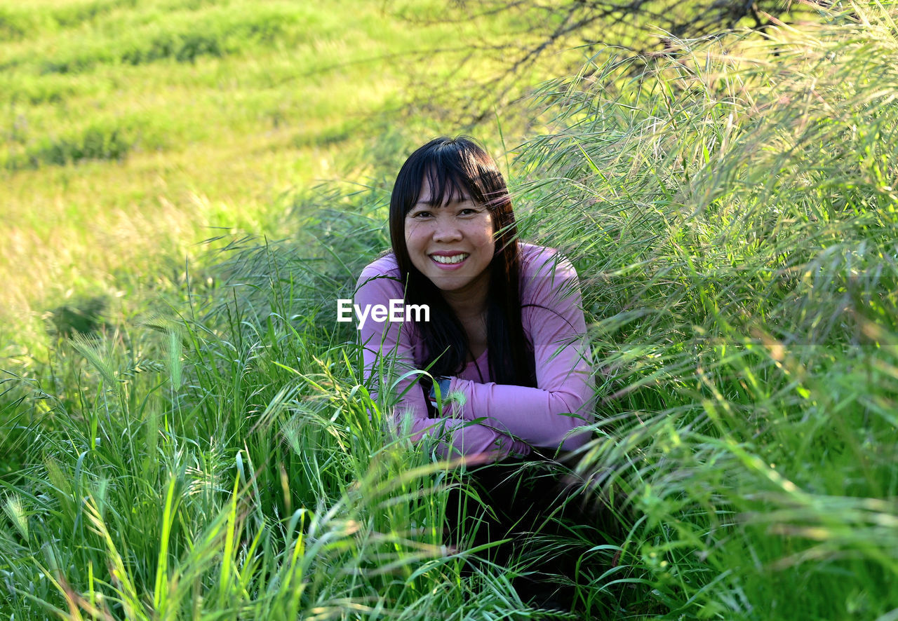 Portrait of smiling woman sitting on field