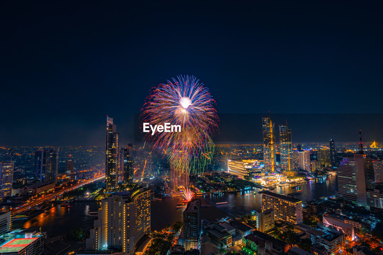 Firework display over city lit up at night. high angle view of illuminated buildings 