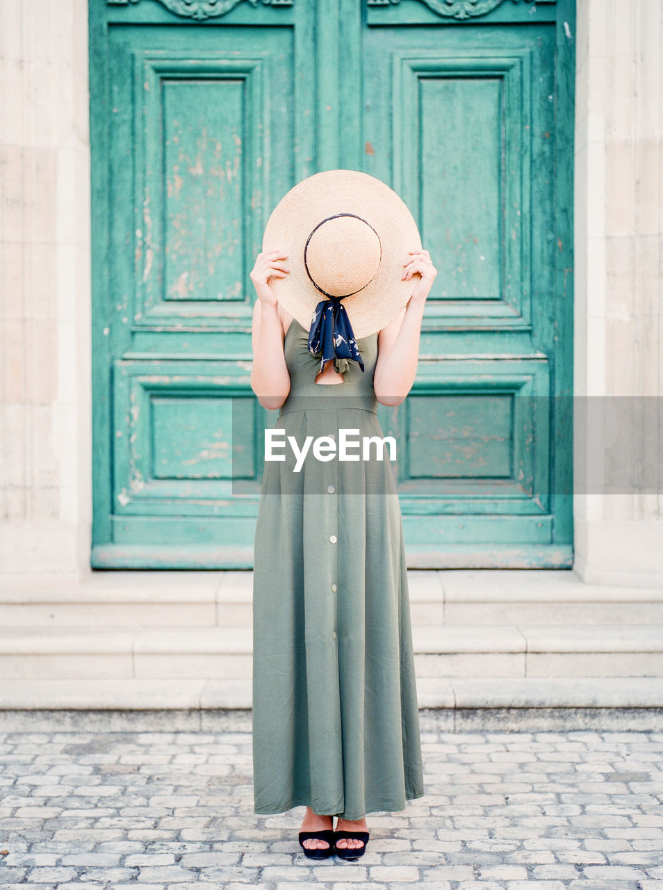 Woman with hat standing against door