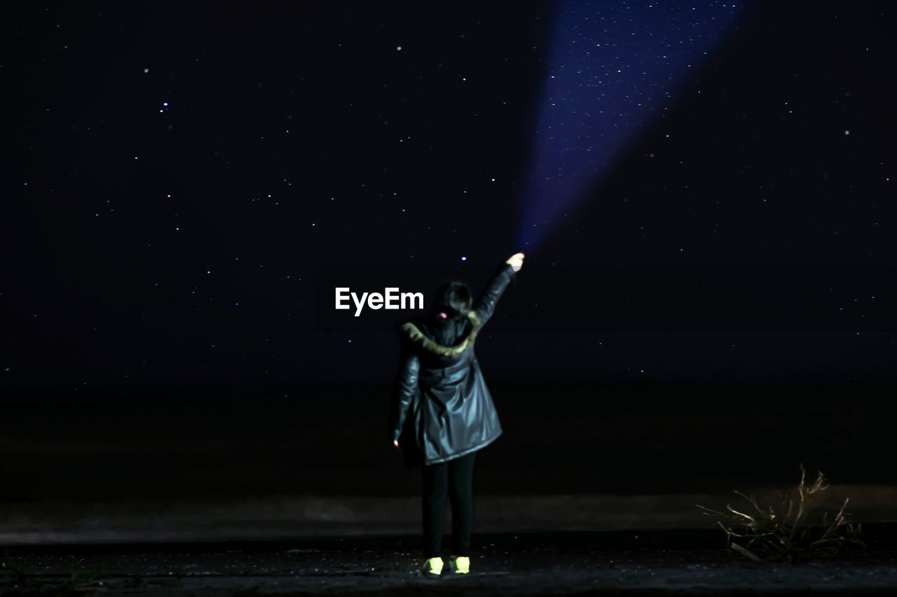 Woman standing against sky at night