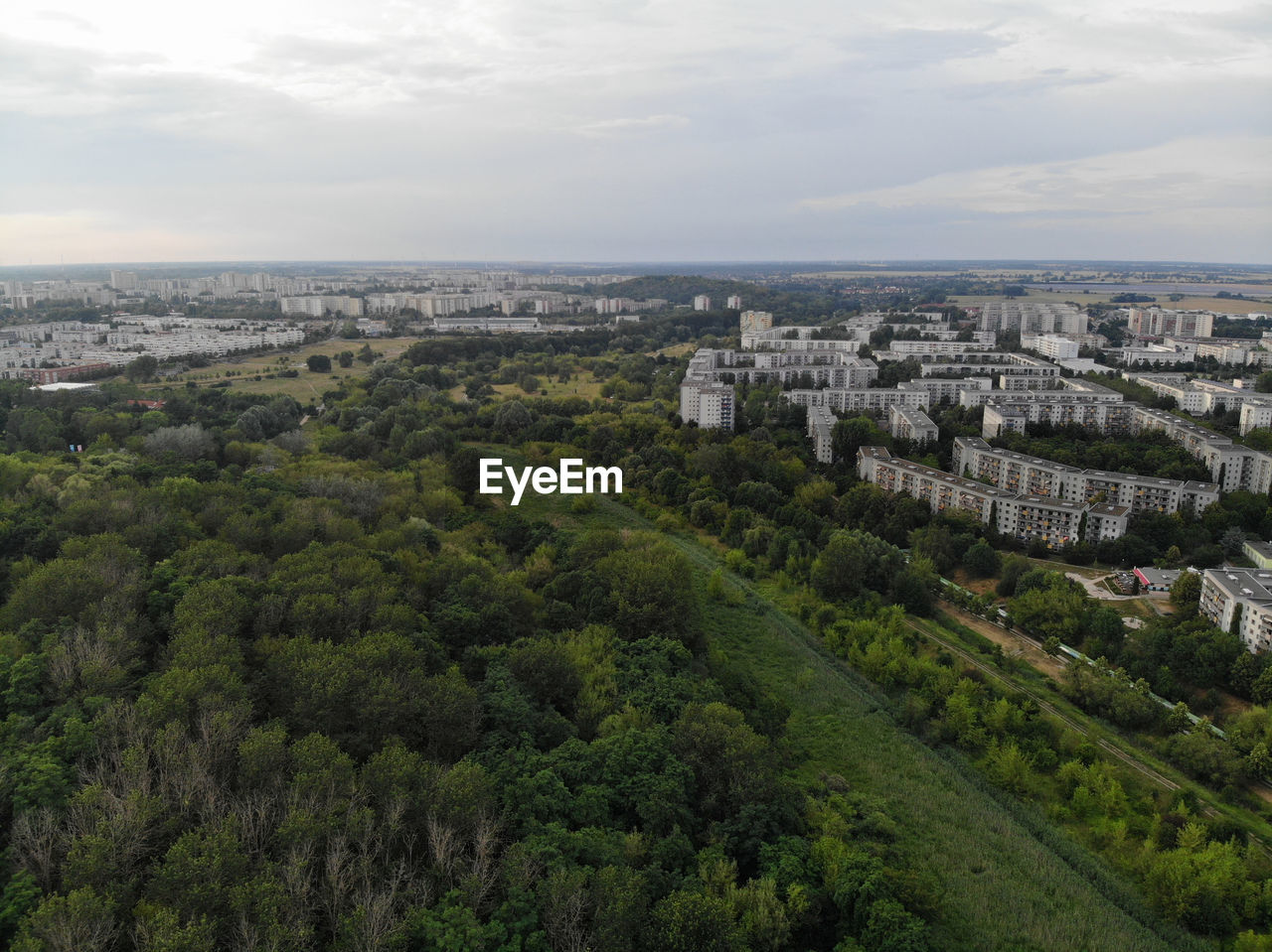 HIGH ANGLE VIEW OF BUILDINGS AND TREES AGAINST SKY