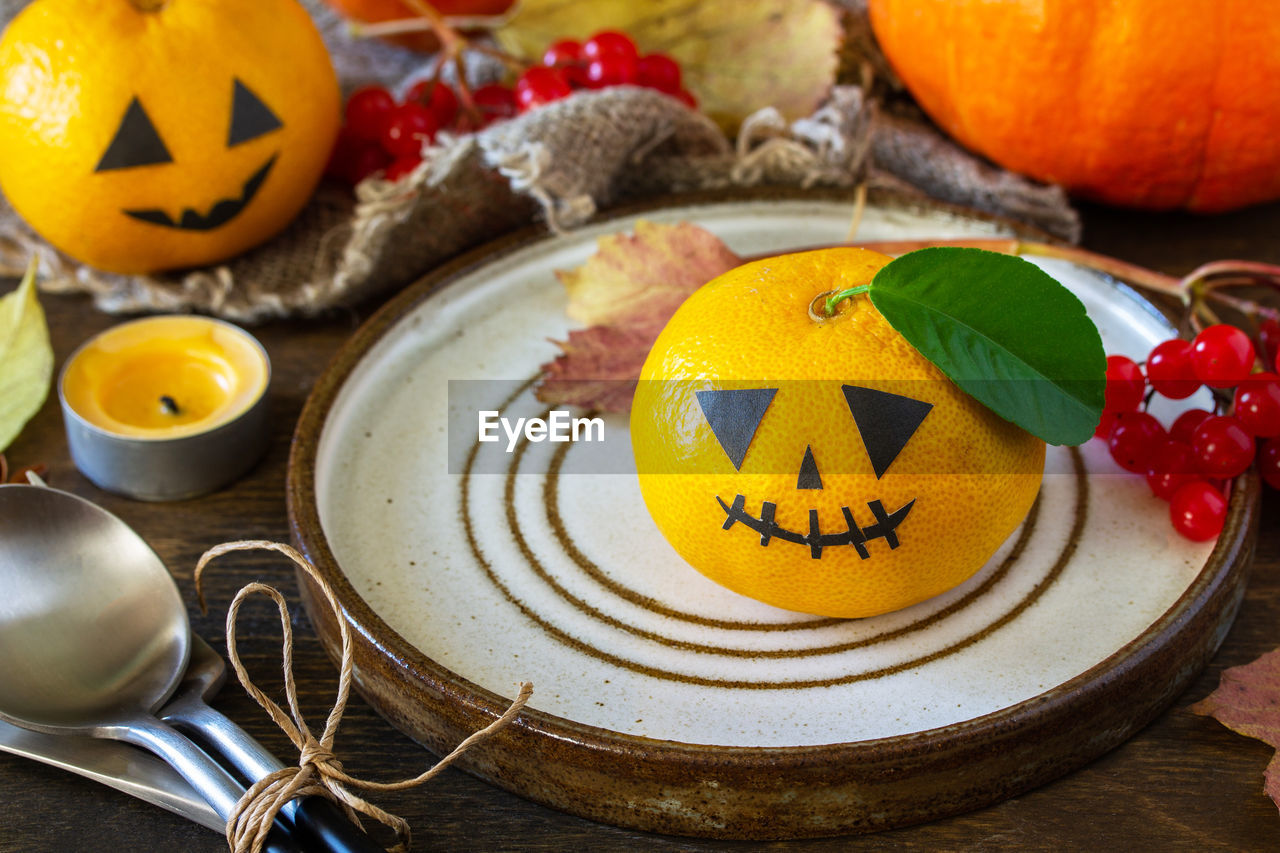 Halloween day decoration party. halloween wooden table setting with pumpkins and tangerines.