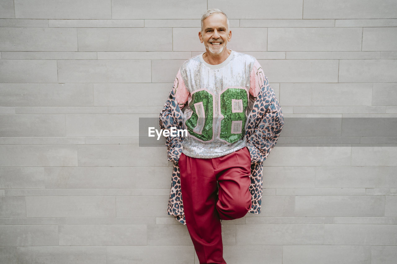 Portrait of mature gay man standing against wall