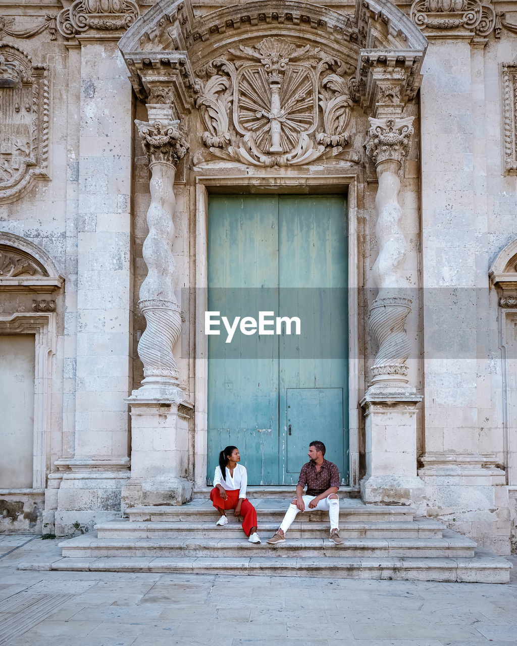 PEOPLE SITTING ON BUILDING ENTRANCE TO DOOR