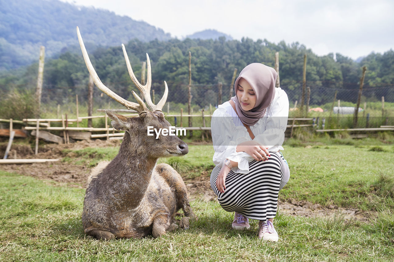 Beautiful asian girl playing with a deer at rancaupas, ciwidey, bandung, indonesia