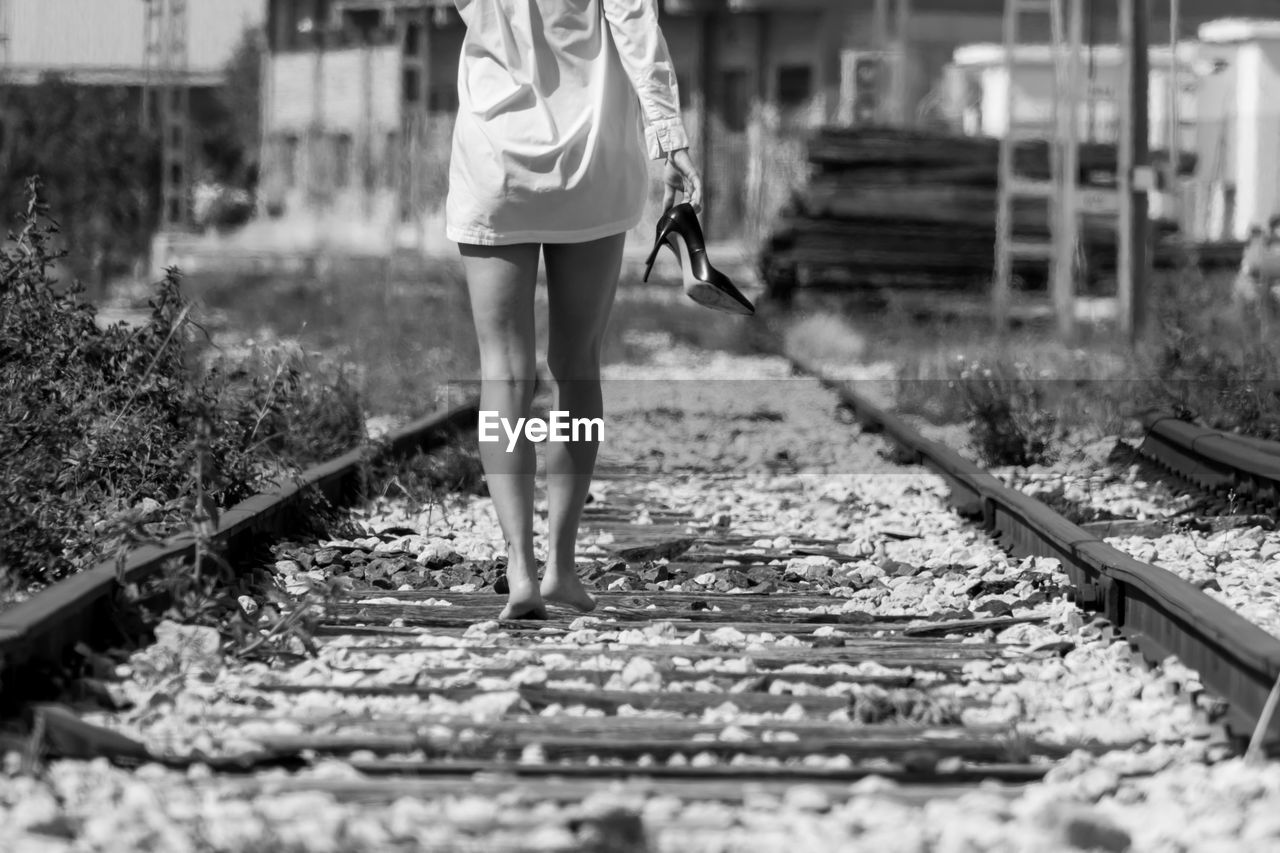Low section of woman walking on railroad track