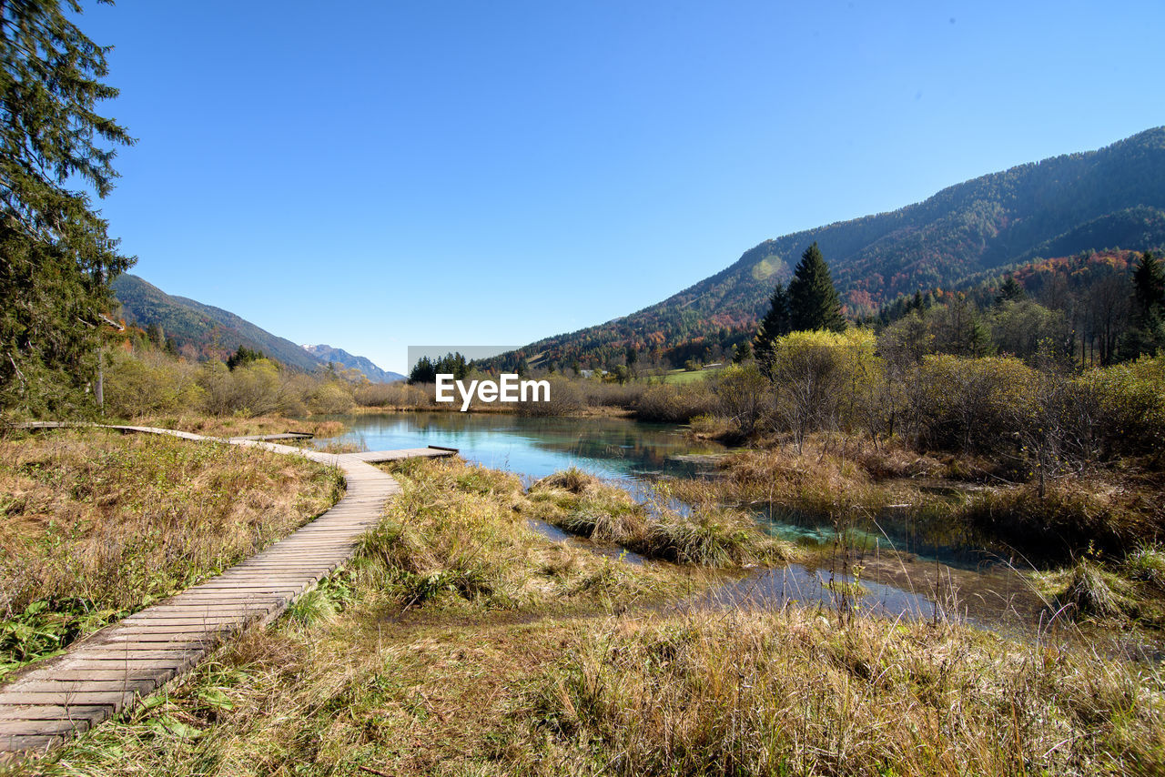 Scenic view of lake and mountains against clear blue sky