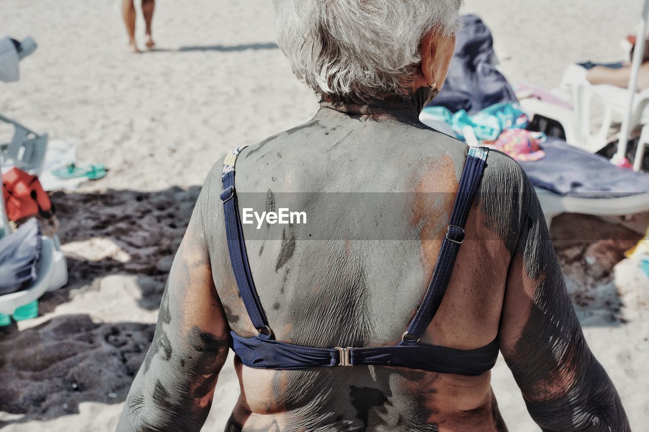 Rear view of woman with sand standing outdoors