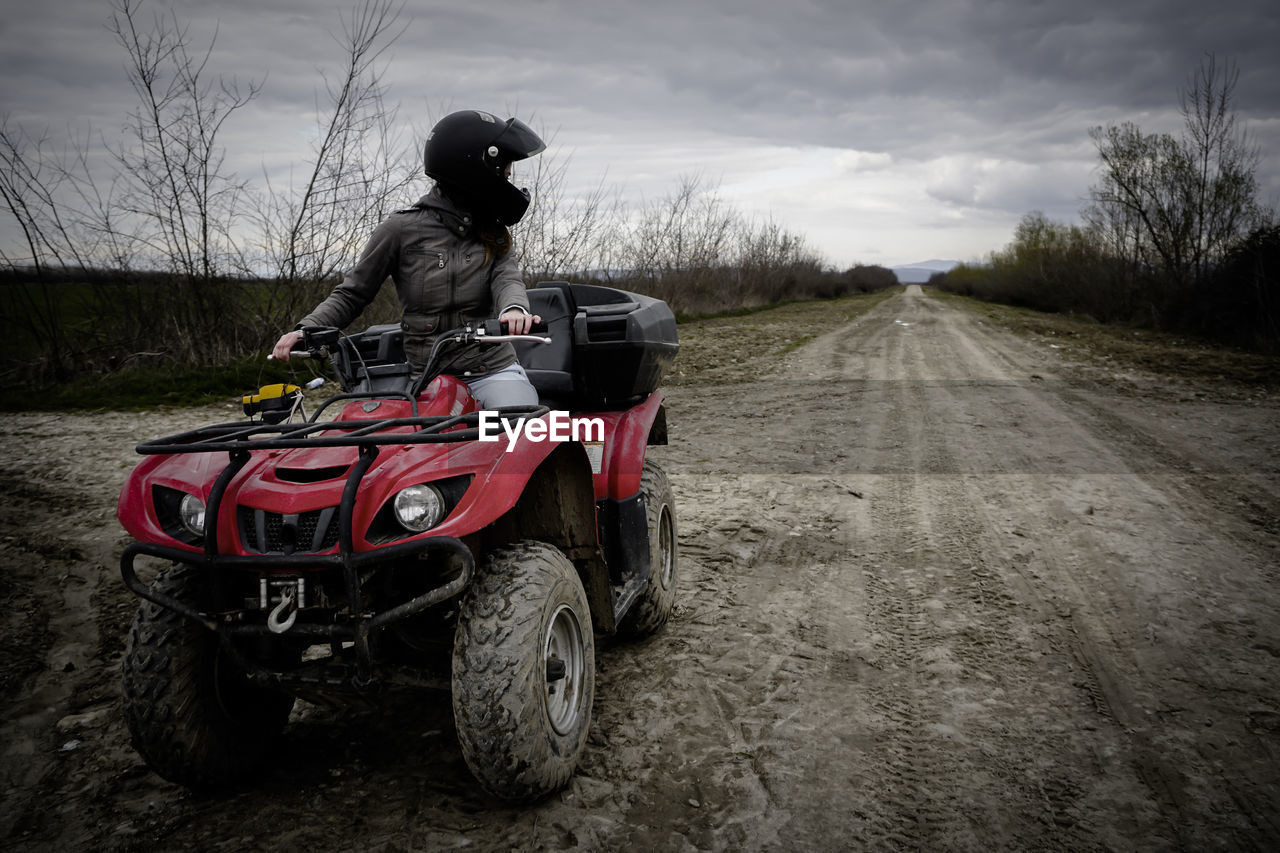 Man riding quadbike on field against sky