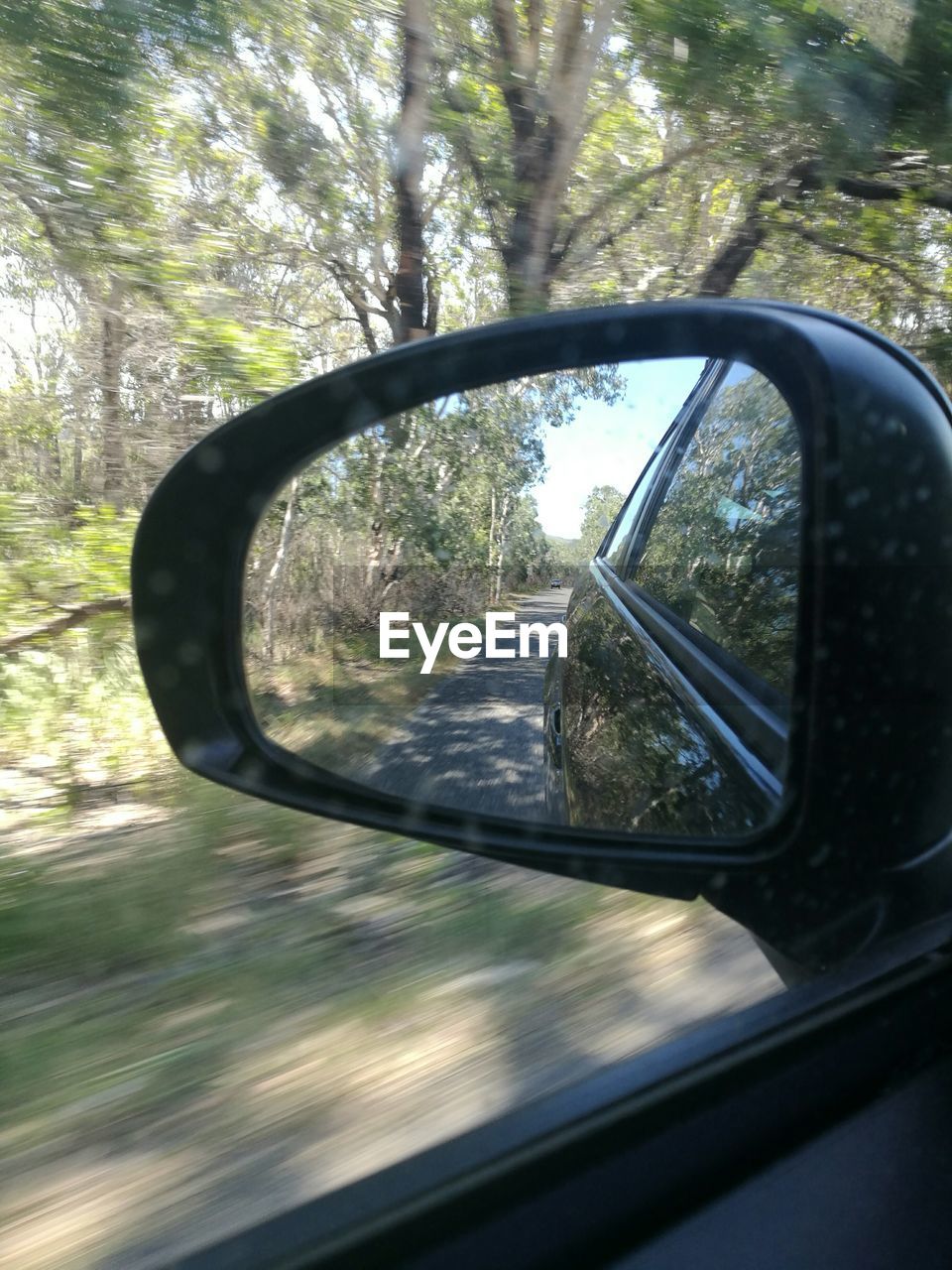 CLOSE-UP OF SIDE-VIEW MIRROR OF CAR