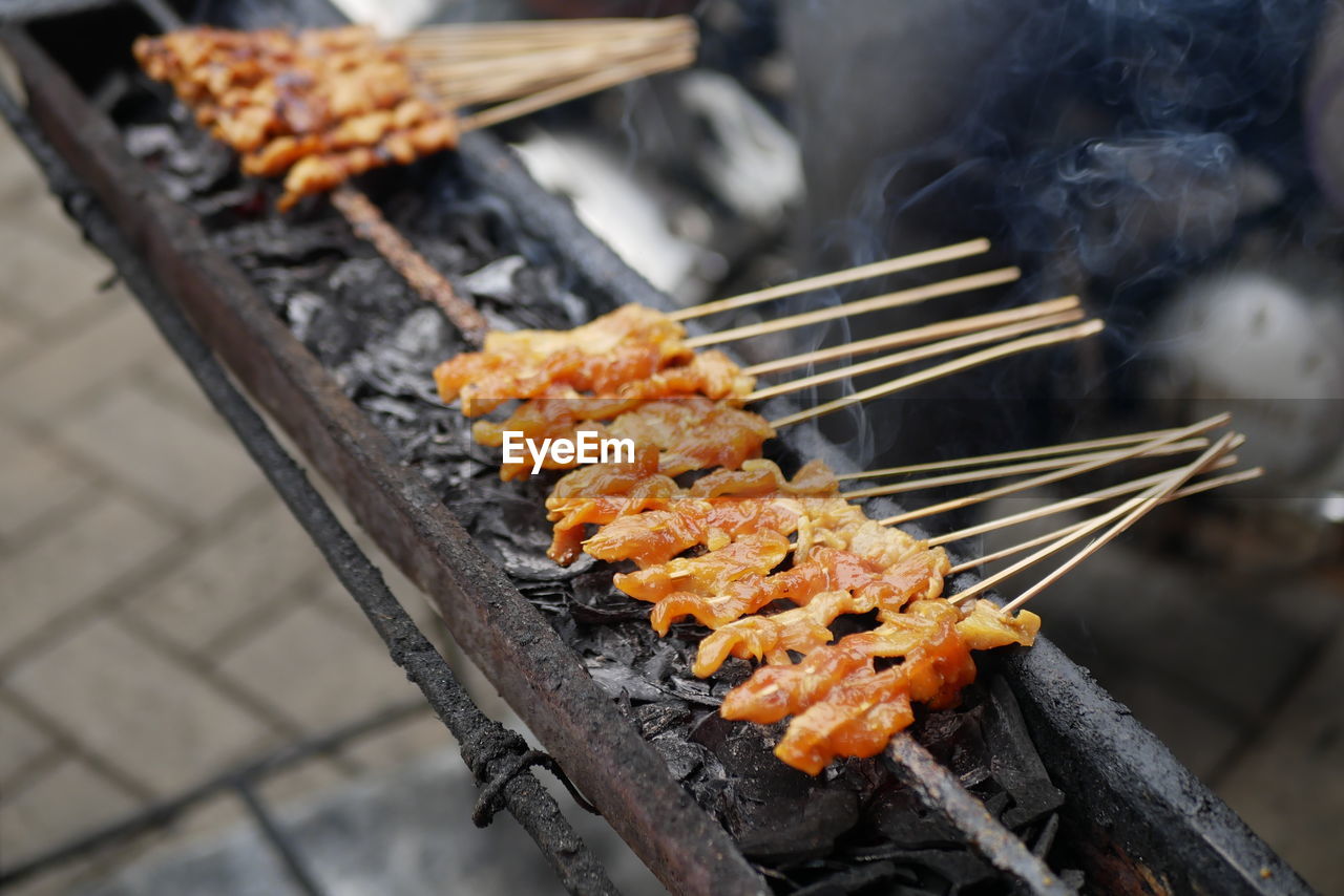 A process of grilling a few ribs of blurry chicken satay over noisy or grainy of black charcoal