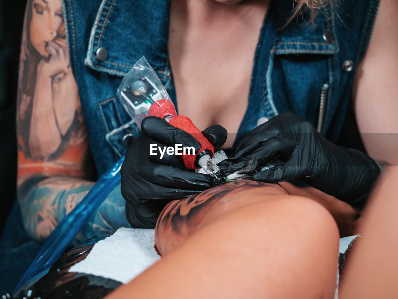 Midsection of tattooist making tattoo on customer