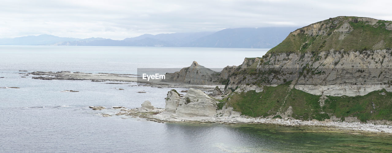 SCENIC VIEW OF SEA BY MOUNTAIN AGAINST SKY