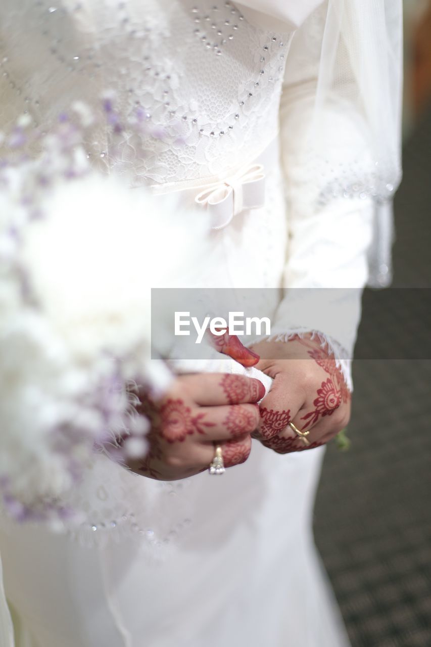 Midsection of bride wearing wedding dress