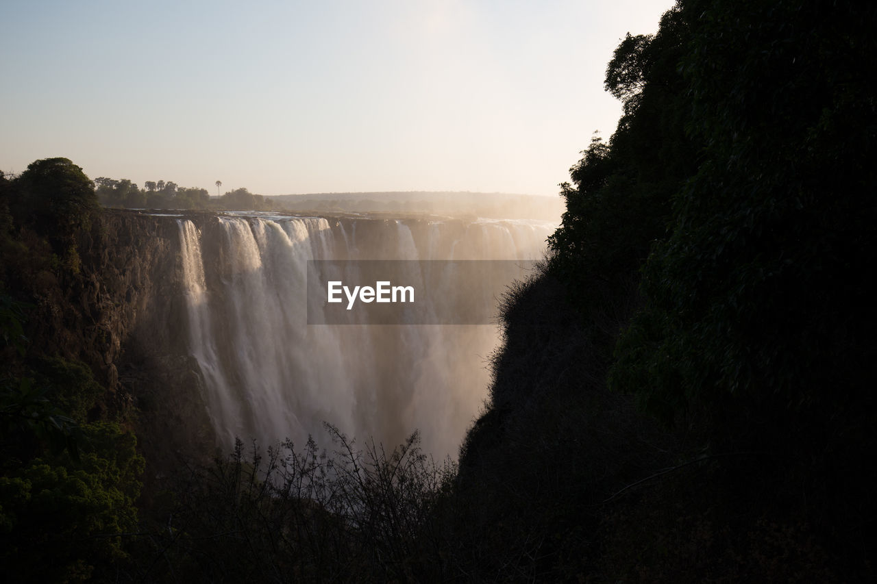 IDYLLIC VIEW OF WATERFALL AGAINST SKY