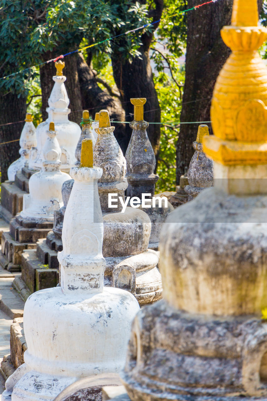 BUDDHA STATUE BY TREES AGAINST BUILDING