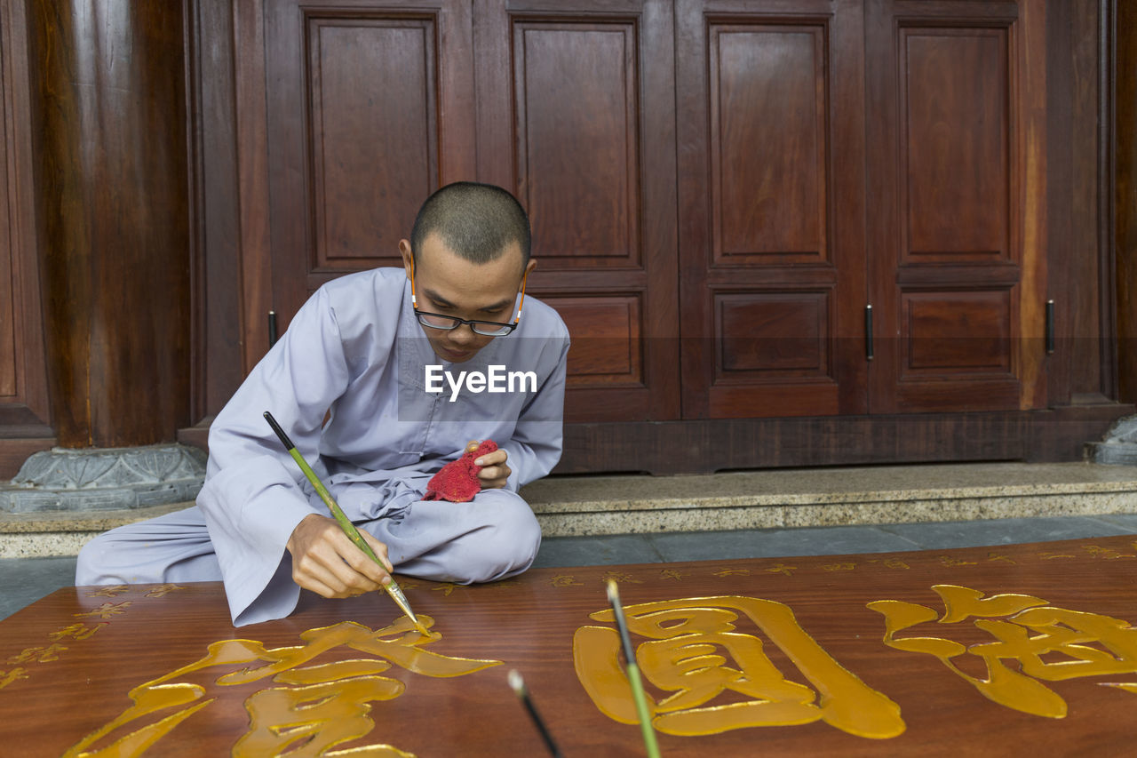 Young monk in temple painting on a board
