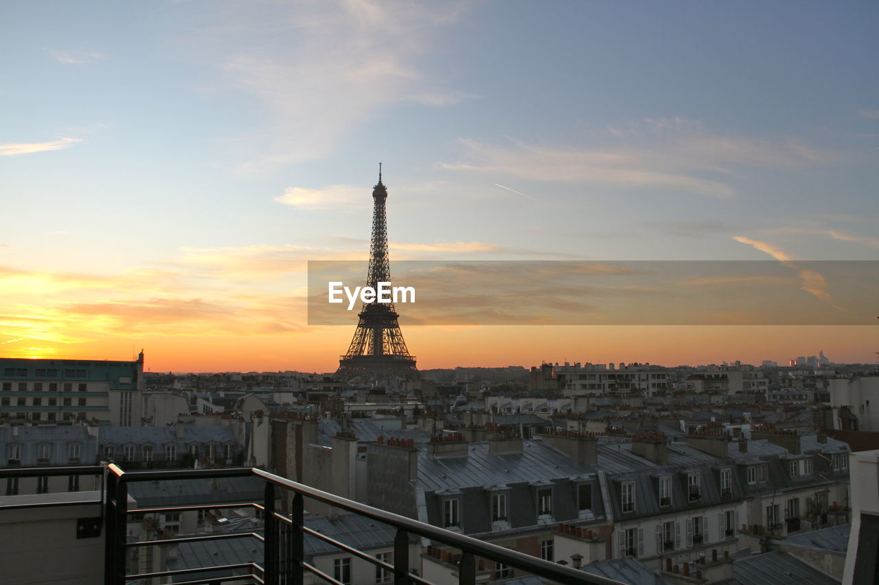 Eiffel tower amidst cityscape against sky during sunset