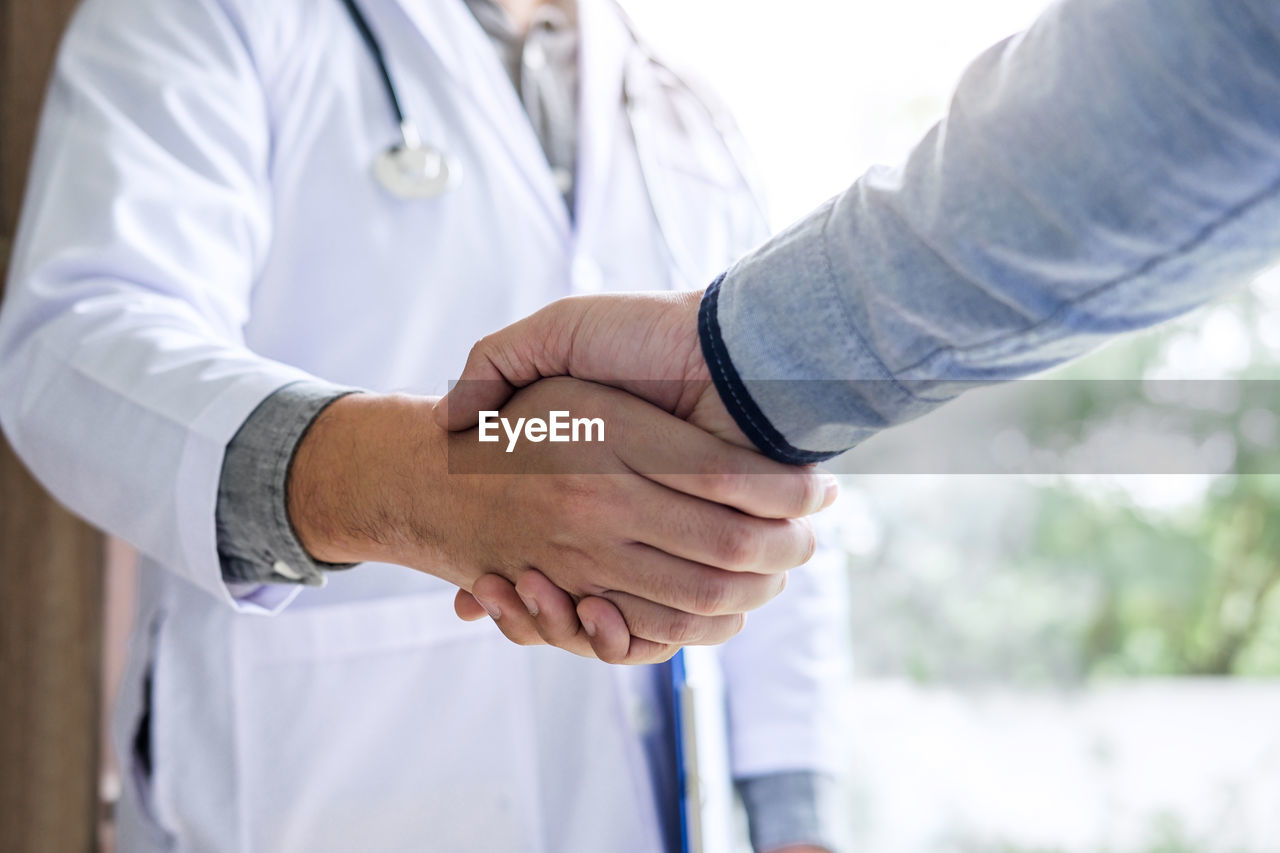Midsection of man shaking hands with doctor