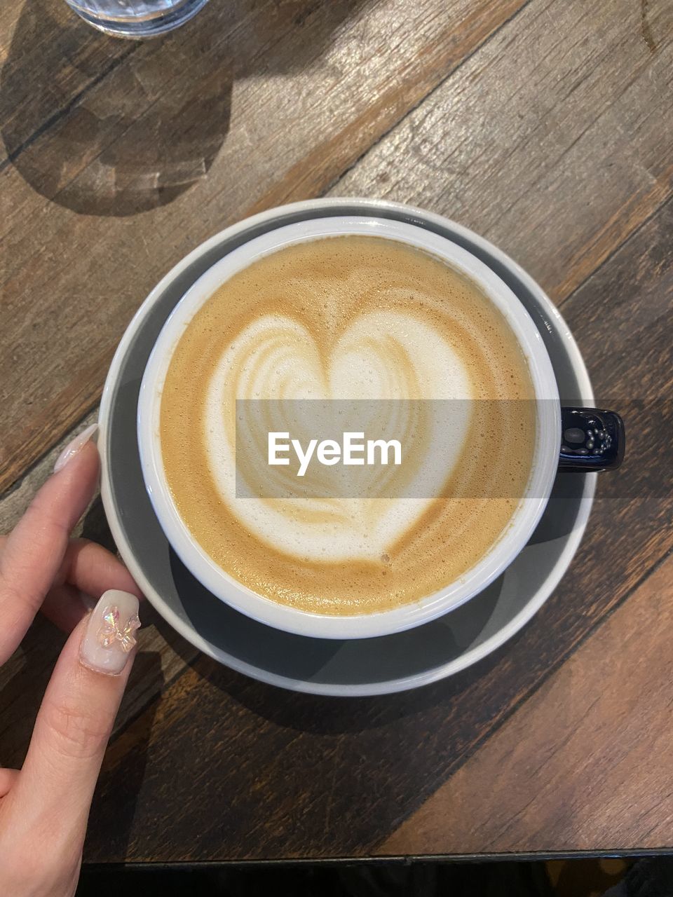 Cropped hand of person holding coffee on table