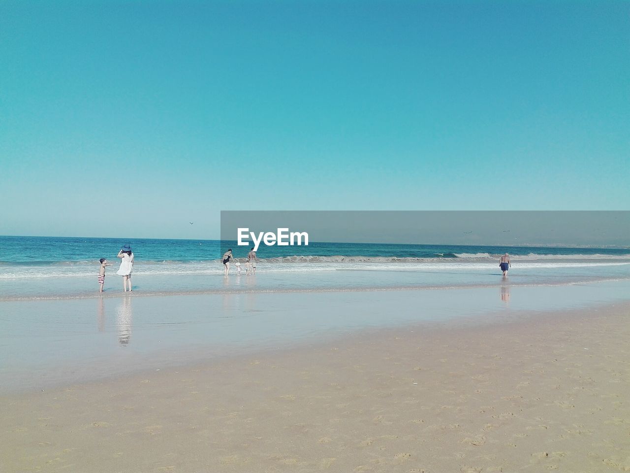 People at beach against clear sky