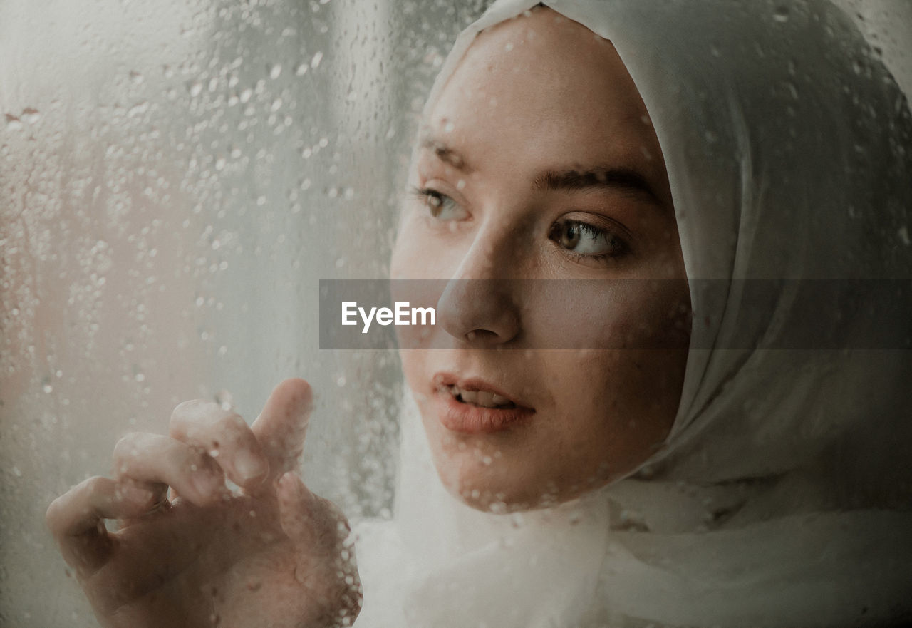 Close-up of woman by wet glass