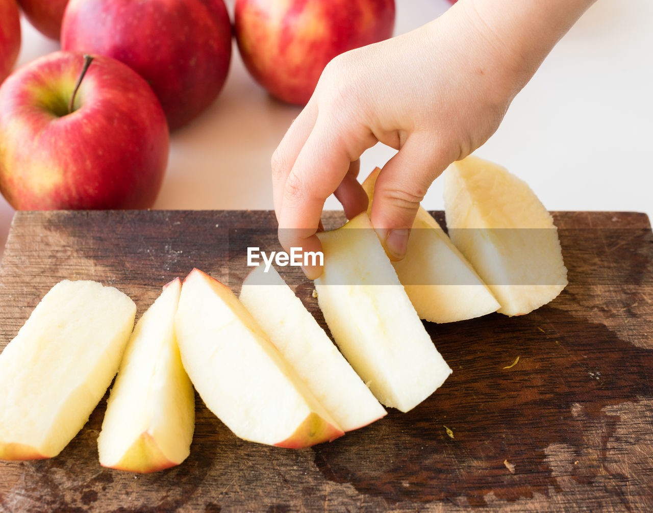 Cropped hand of child holding apple on cutting board