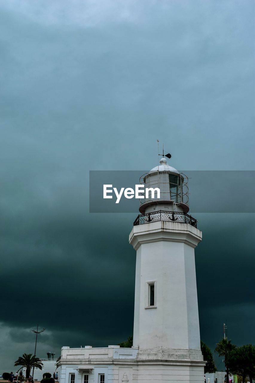 Low angle view of lighthouse by building against sky