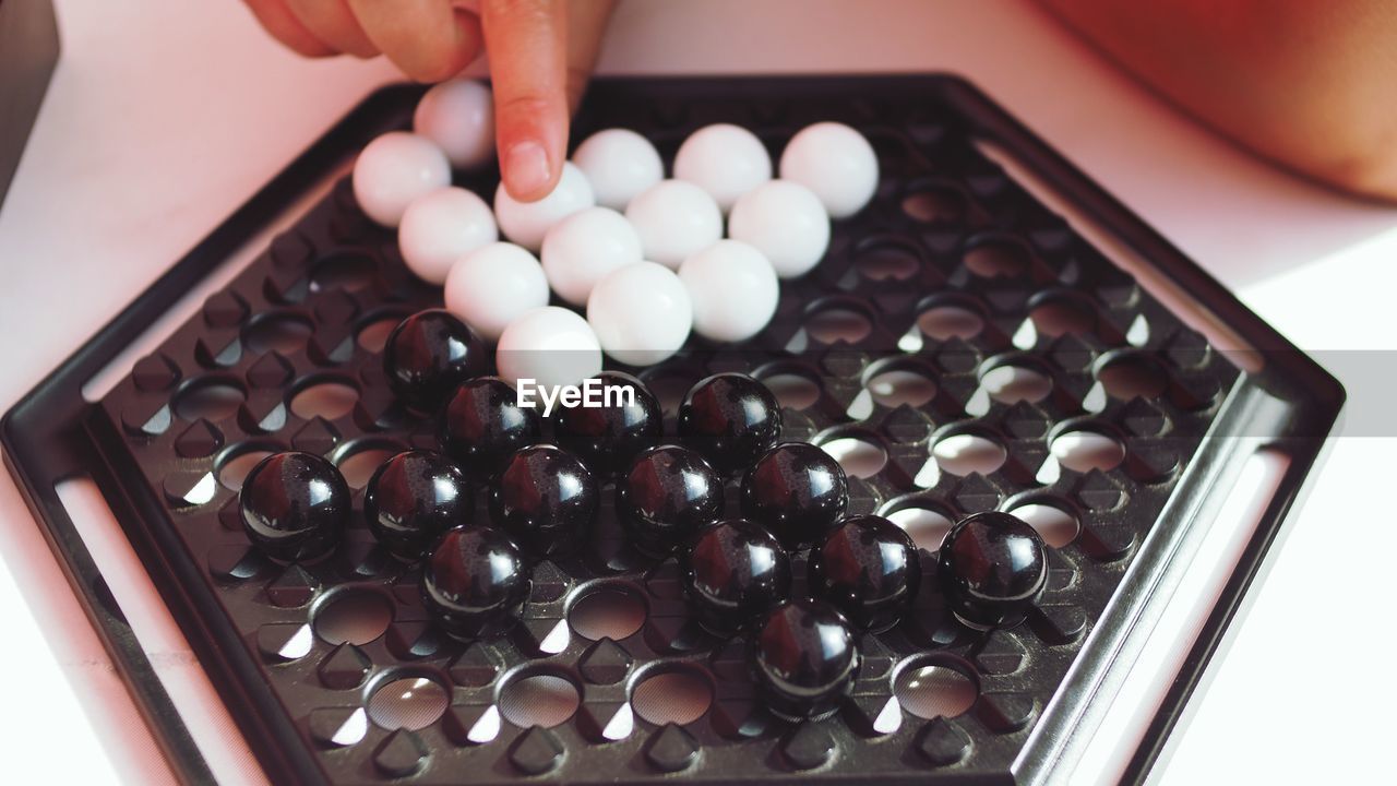 HIGH ANGLE VIEW OF PERSON HAND HOLDING CANDIES IN CONTAINER