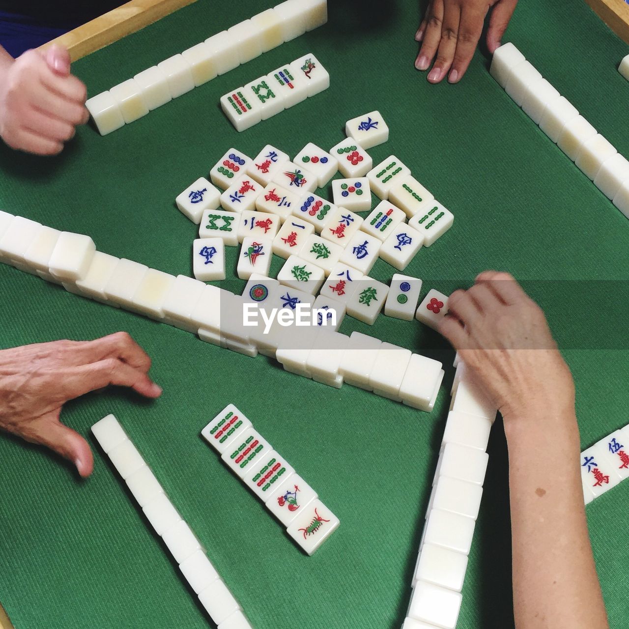 Cropped image of people playing mahjong on table