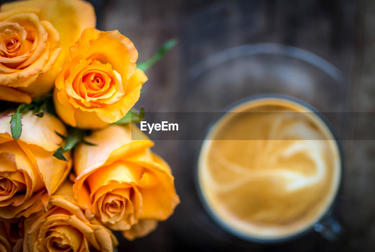 Close-up of yellow roses with coffee in background