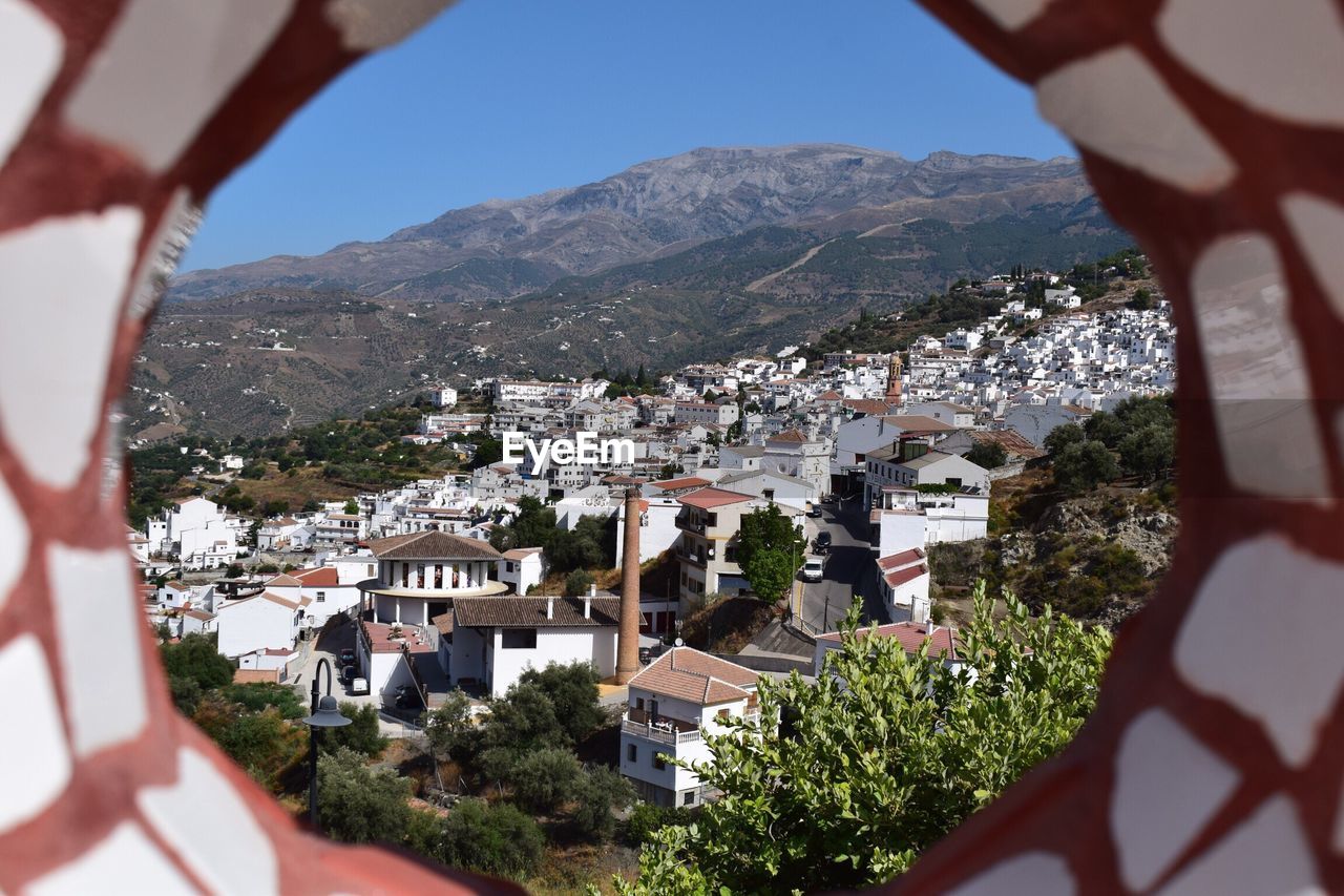 Aerial view of townscape and mountains against sky