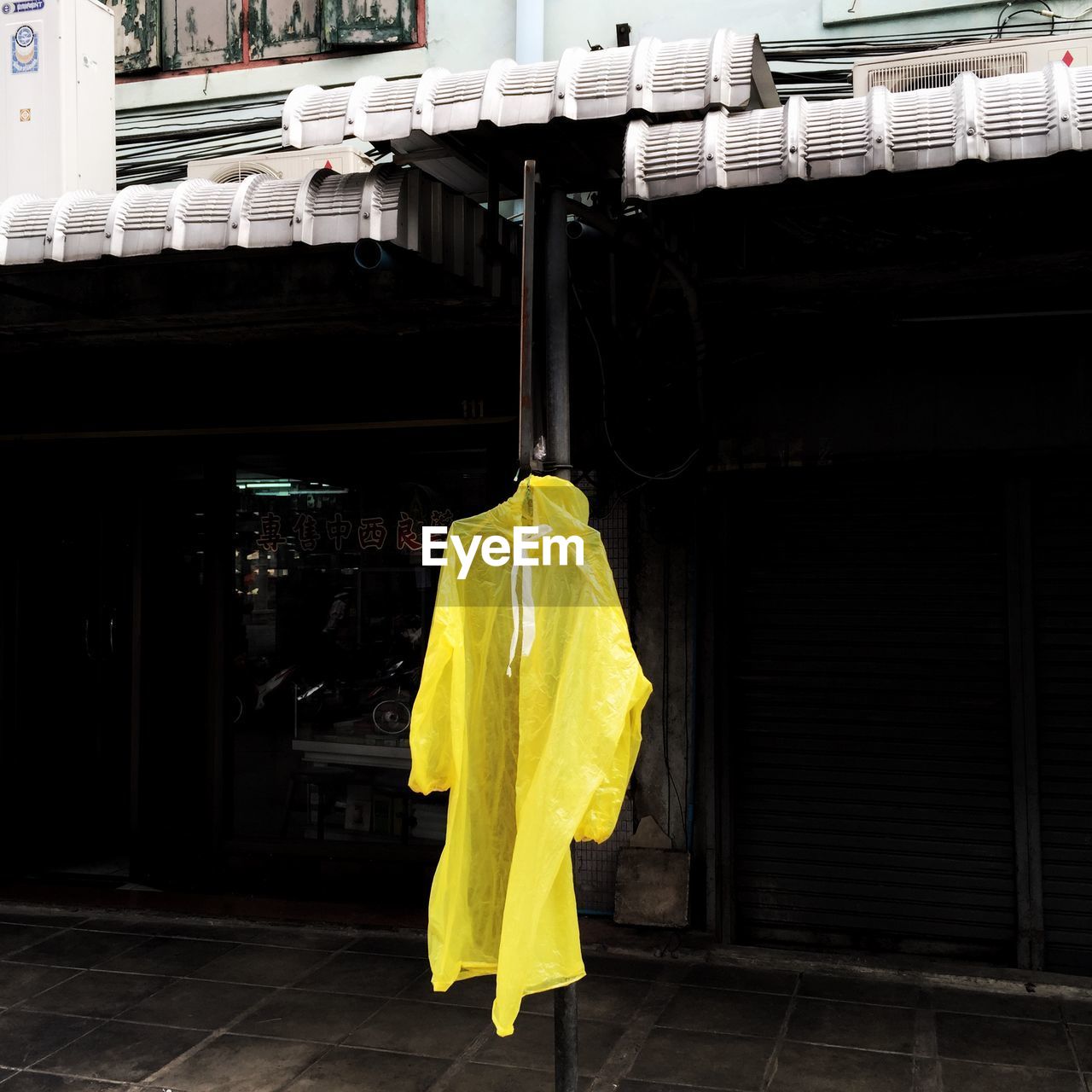 Yellow raincoat on pole against store