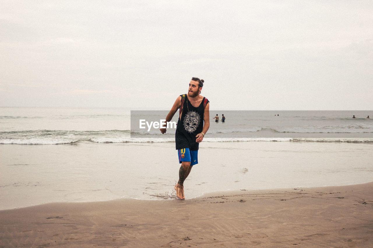 Full length of young man tourist walking at beach