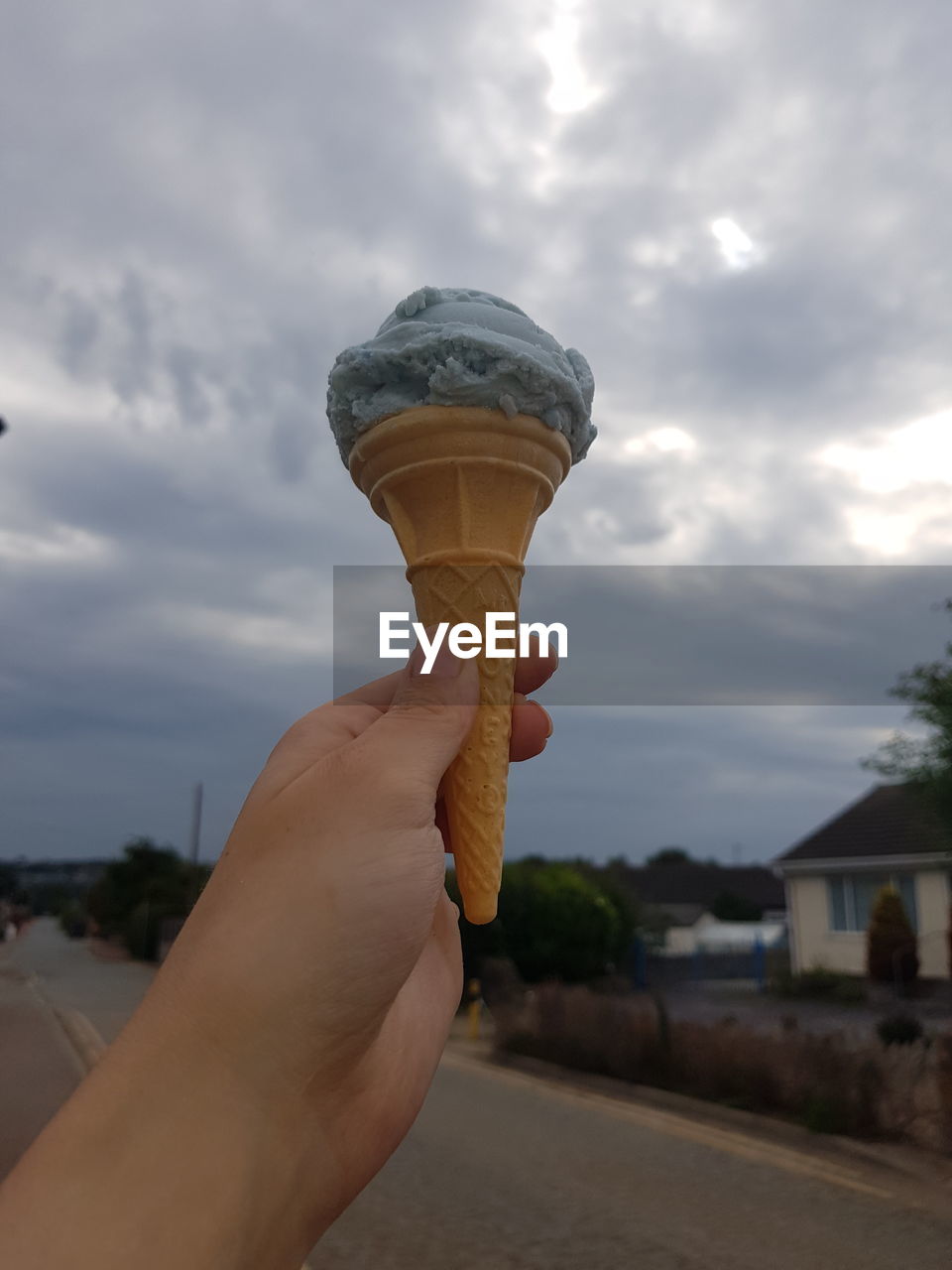 PERSON HOLDING ICE CREAM CONE AGAINST SKY