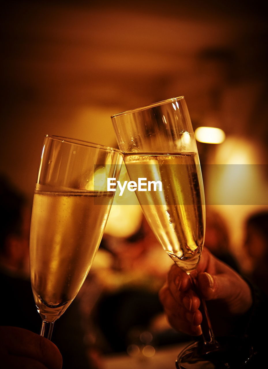 Close-up of champagne flutes toasting at night