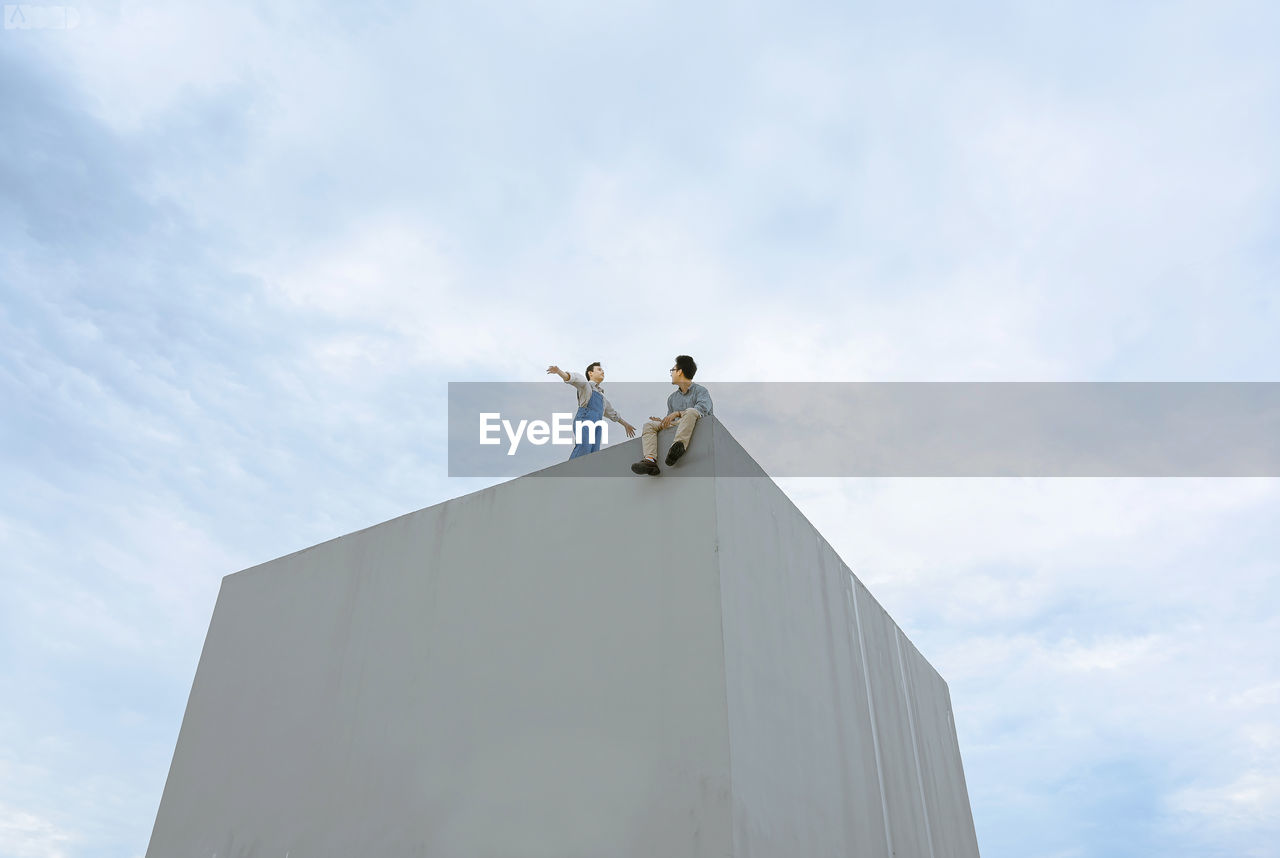 LOW ANGLE VIEW OF PEOPLE STANDING ON BUILDING