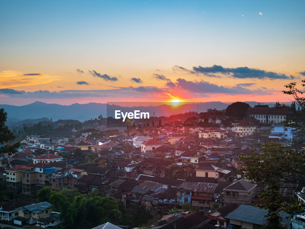 HIGH ANGLE SHOT OF TOWNSCAPE AGAINST ORANGE SKY